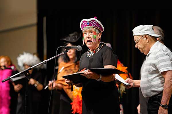 The Dells Angels Choir members hold song books and sing together on stage.