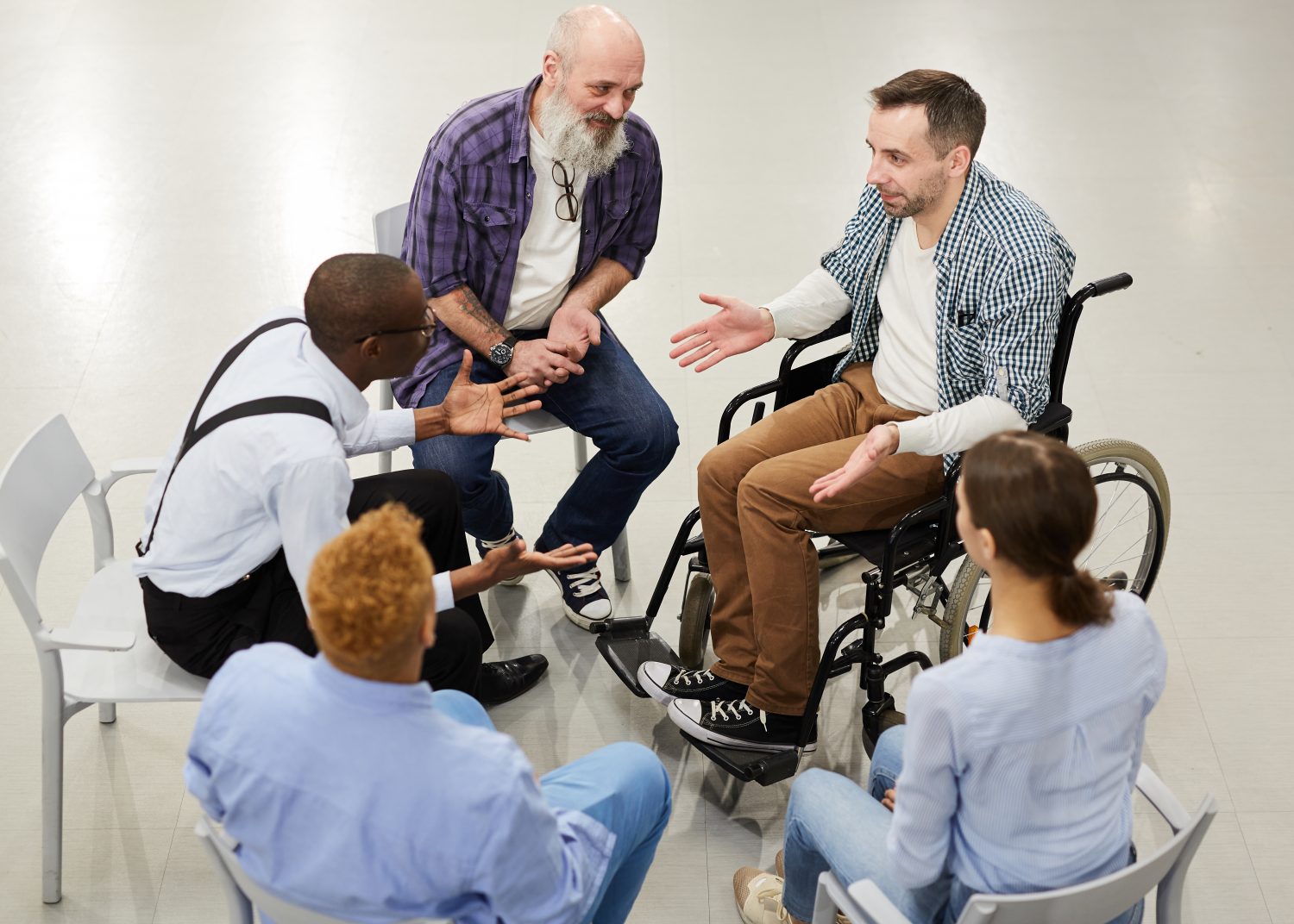 Man in a wheelchair is talking to a small support and counseling group.