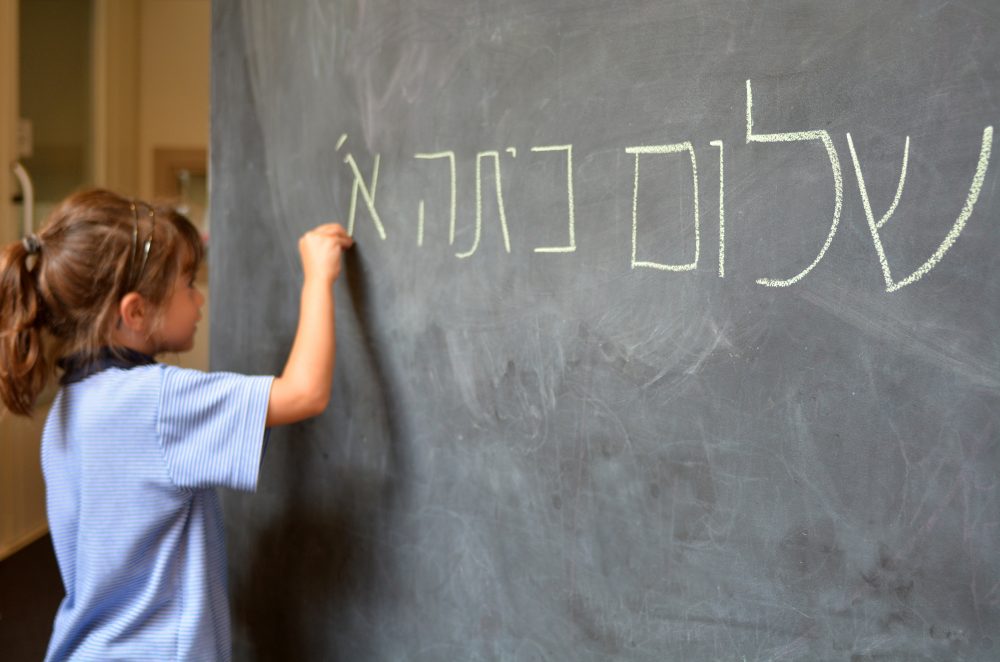 A child writes a Hebrew word on the chalkboard at a Jewish school