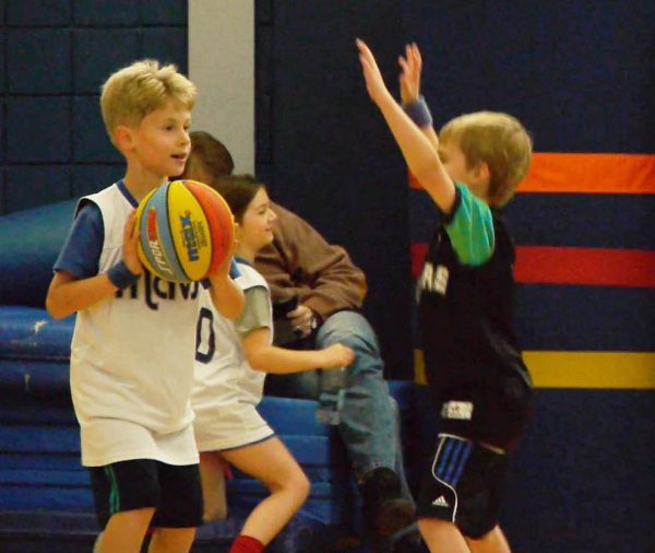 Two boys play basketball together in the gym