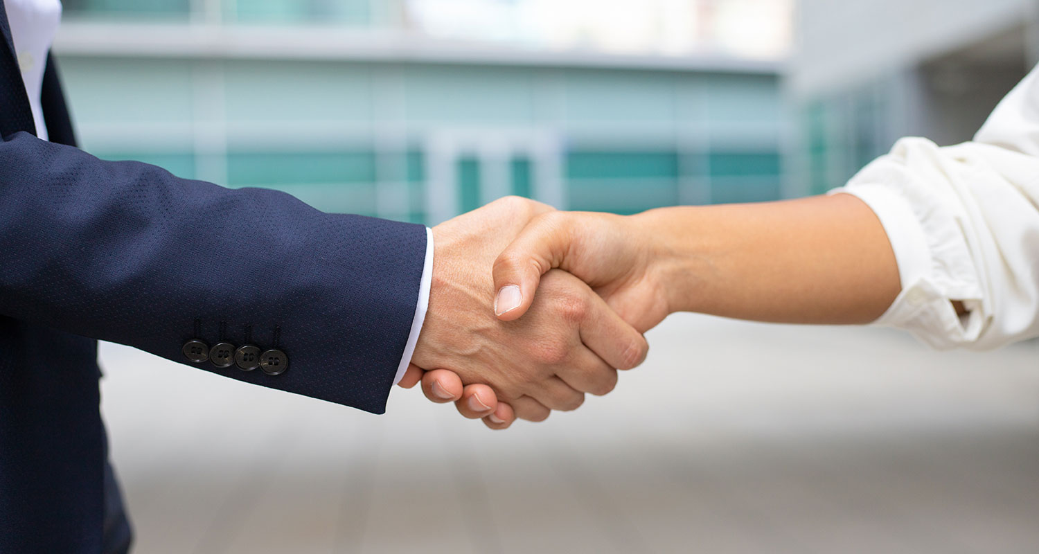 Two people wearing business suits shake hands