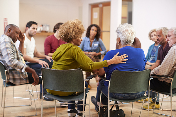 People Attending Self Help Therapy Group Meeting In Community Center Professional woman meditating at her work desk