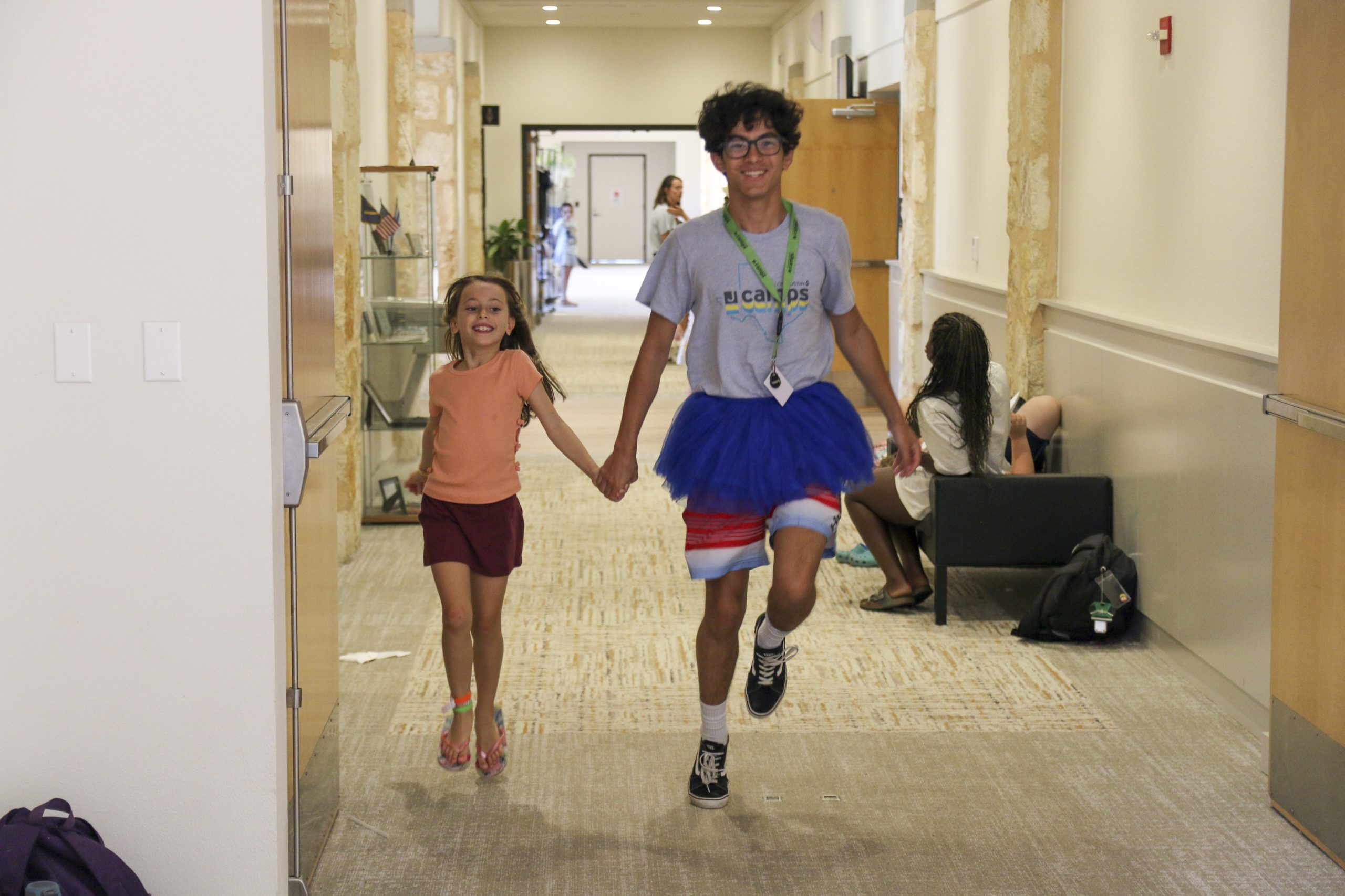Camp counselor skipping down the hall with kid
